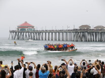 Sixty-six surfers from around the world ride a custom built 42-foot, 1300 pound surfboard for 12 seconds to break the GUINNESS WORLD RECORDS® for “Most People Riding a Surfboard at Once” on Saturday, June 20, 2015 in Huntington Beach, California.The surfboard, which thousands of spectators filled the Surf City USA shoreline to see, is also expected to break an additional record, "Largest Surfboard,” after official confirmation from GUINNESS WORLD RECORDS®. (Danny Moloshok/AP Images for Visiting Huntington Beach)