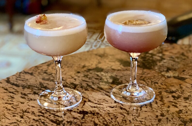 Two champagne coupes are filled with a pale tan liquid.