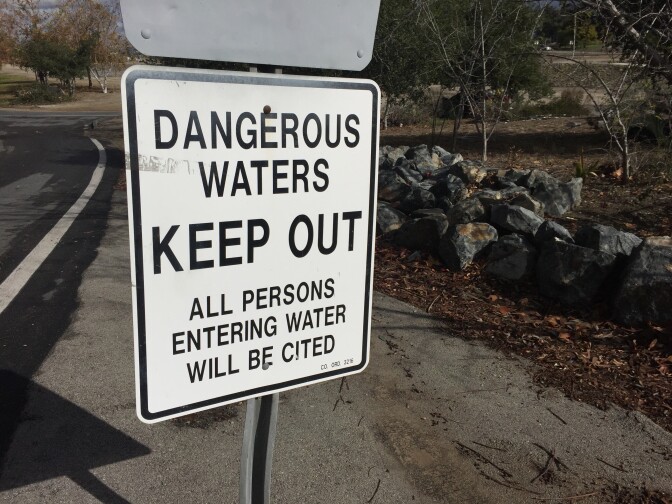 Signs warn visitors to the Santa Ana River Trail in Orange that anyone who wades into storm flood waters in the riverbed will be ticketed. January 7, 2015.