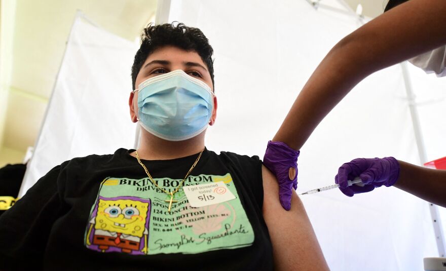 Hamilton Bermudez, 14, receives his Pfizer Covid-19 vaccine administered by medical assistant Karina Cisneros from St. John's Well Child & Family Center at Abraham Lincoln High School in Los Angeles, California on May 13, 2021, on the first day of availability of the vaccine for the 12-15 year old age group. - The campaign to immunize America's 17 million adolescents aged 12-to-15 kicked off in full force on May 13, a key part of President Joe Biden's strategy to push the country close to herd immunity. (Photo by Frederic J. BROWN / AFP) (Photo by FREDERIC J. BROWN/AFP via Getty Images)