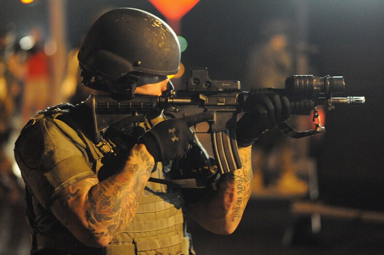 A law enforcement officer watches on during a protest on West Florissant Avenue in Ferguson, Missouri on August 18, 2014. Police fired tear gas in another night of unrest in a Missouri town where a white police officer shot and killed an unarmed black teenager, just hours after President Barack Obama called for calm. 
