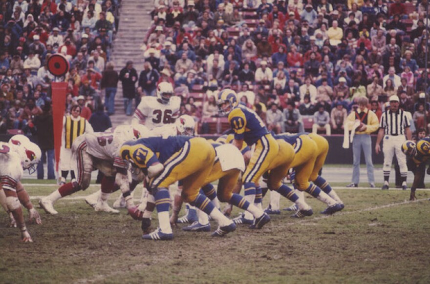 Football players face off at the line of scrimmage.