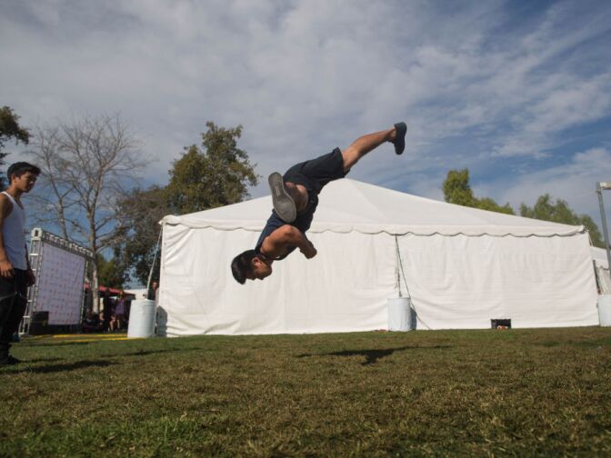 Brian Le, 19, of Westminster practices martial arts tricking in a yard behind a tent at the Verizon Ampitheatre.