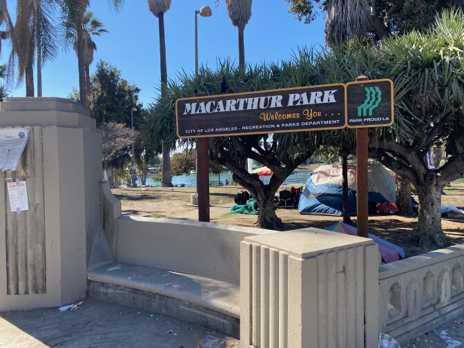 The entry sign to the lakeside portion of MacArthur Park. Tents are visible in the background.