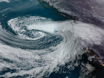 Satellite image of huge swirling white clouds over the ocean and the west coast of the United States