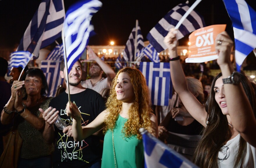 People celebrate in Athens on July 5, 2015 after the first exit-polls of the Greek referendum. Over 60 percent of Greeks rejected further austerity dictated by the country's EU-IMF creditors in a referendum, results from 20 percent of polling stations showed. AFP PHOTO / LOUISA GOULIAMAKI        (Photo credit should read LOUISA GOULIAMAKI/AFP/Getty Images)