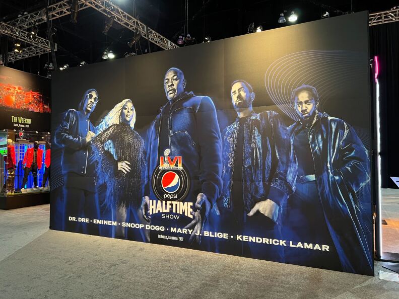 A large illustrated banner of the 2022 Super Bowl Halftime performers --- Dr. Dre, Eminem, Snoop Dogg, Mary J. Blige and Kendrick Lamar -- is on display at the Super Bowl Experience.