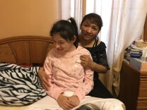 Rosa Andresen, in back, holds her daughter, Amanda Andresen, in their South Gate home. 