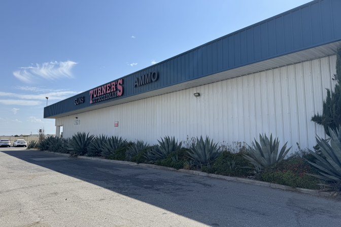 Turner's Outdoorsman storefront with 'Guns' and 'Ammo' signage, desert plants line the building's exterior.