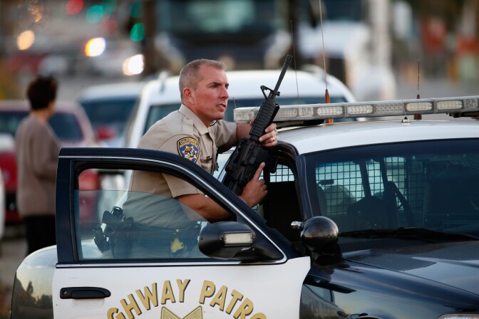 SAN BERNARDINO, CA - DECEMBER 02: A California Highway Patrol officer stands with his weapon as authorities pursued the suspects in a shooting that occurred at the Inland Regional Center on December 2, 2015 in San Bernardino, California.  Police continue to search for suspects in the shooting that left at least 14 people dead and another 17 injured.   (Photo by Sean M. Haffey/Getty Images)