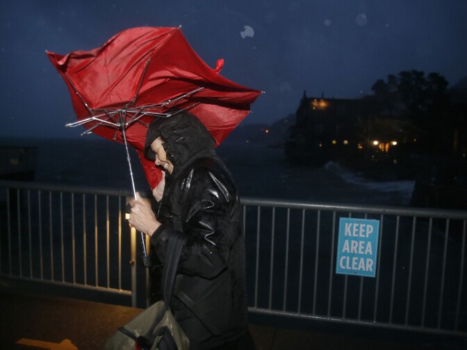 Commuter ML Mann struggles in the wind and rain to make her way to catch a ferry, Thursday, Dec. 11, 2014, to San Francisco from Sausalito, Calif. A storm expected to be one of the windiest and rainiest in five years swept across the San Francisco Bay Area on Thursday, knocking out power to thousands and delaying travel by air, train and ferry. (AP Photo/Eric Risberg)
