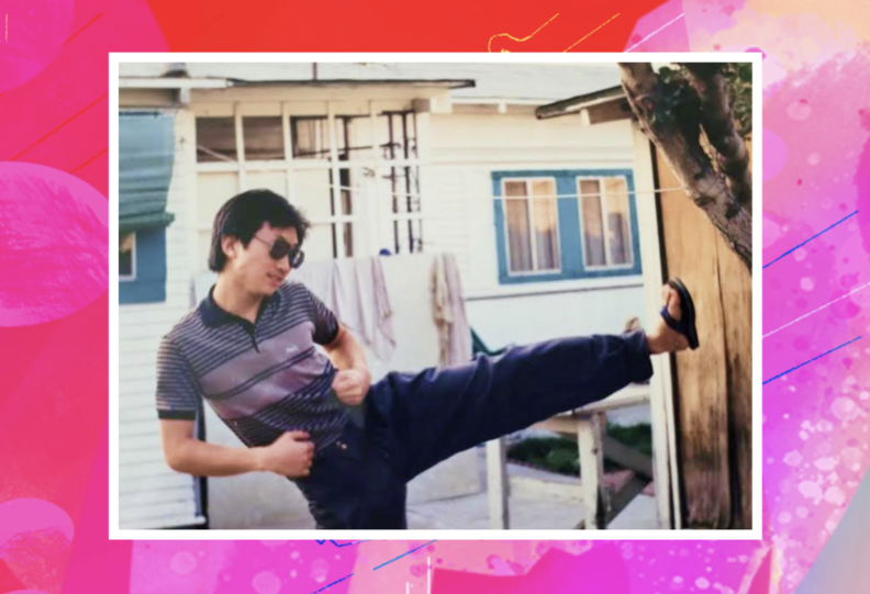 A man in sunglasses doing a high kick martial-arts style, with a white painted house in the background.