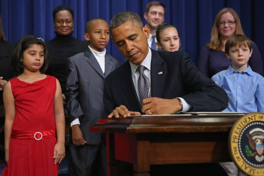 WASHINGTON, DC - JANUARY 16:  U.S. President Barack Obama signs a series of executive orders about the administration's new gun law proposals as children who wrote letters to the White House about gun violence, (L-R) Hinna Zeejah, Taejah Goode, Julia Stokes and Grant Fritz, look on in the Eisenhower Executive Office building January 16, 2013 in Washington, DC. One month after a massacre that left 20 school children and 6 adults dead in Newtown, Connecticut, the president unveiled a package of gun control proposals that include universal background checks and bans on assault weapons and high-capacity magazines.  (Photo by Chip Somodevilla/Getty Images)
