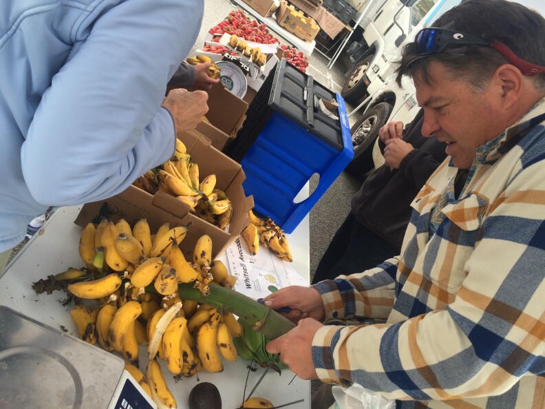 Farmer Andy Shaeffer helps a customer at the Wednesday morning farmers market in Santa Monica. He sells locally grown, "antique" bananas.