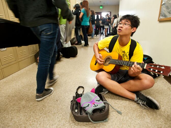 Freshman William Ng, a cello player, plays his friend's guitar in the halls of the new music facility.