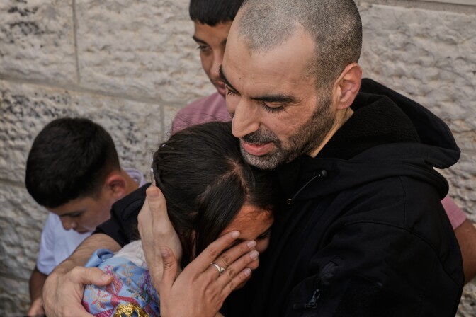 A man and woman embrace in tears. Younger boys stand behind them.