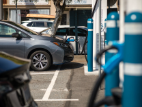 A gray sedan is connected to a charger at an electric vehicle charging station. 