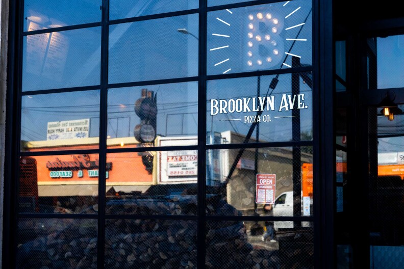A glass store front with painted lettering that reads "Brooklyn Ave. Pizza Co."