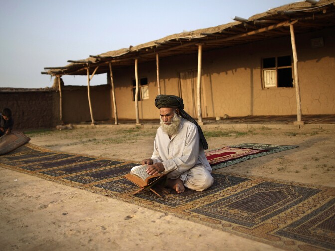 Afghan refugee Hamesha Gul, 59, reads from the Quran after early-morning prayer in a mosque in an Islamabad slum in August.