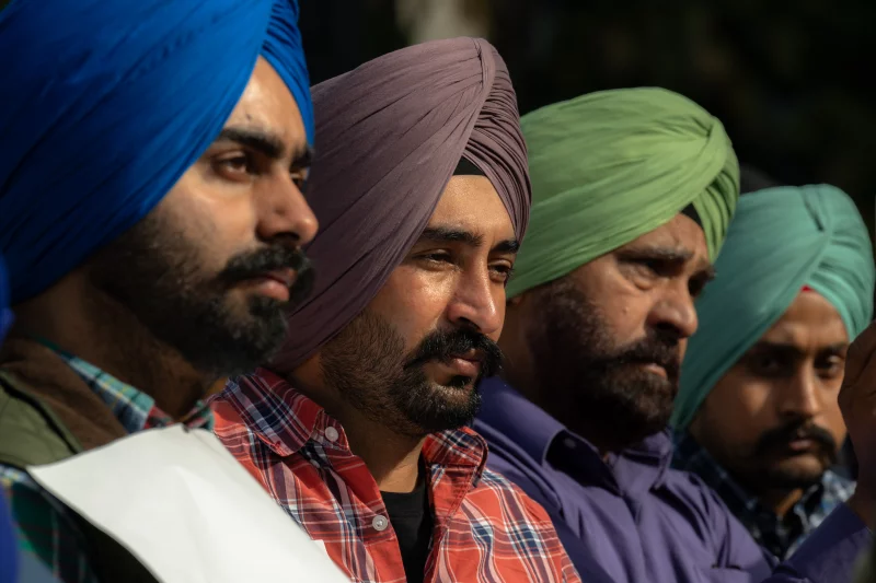 Four people with mustaches and beards wearing different colorful turbans