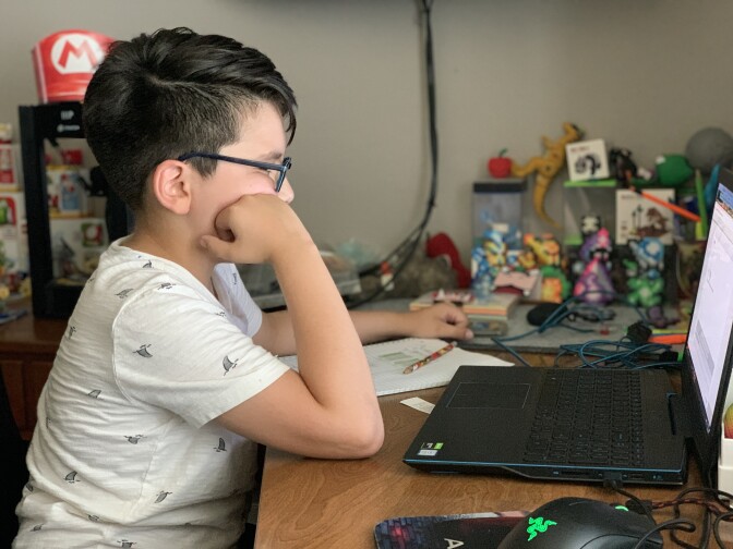 A student sits in front of a laptop for a distance learning lesson.