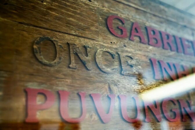 A sign displayed behind glass noting that the campus of CSU Long Beach sits on Puvungna, the site of an ancient Tongva/Gabrielino village. 