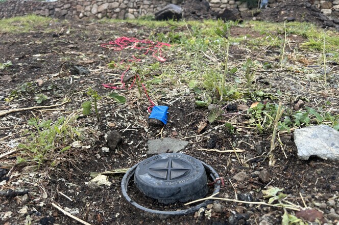 A small black cap in the dirt ground, marking the location of a resident's cesspool. 