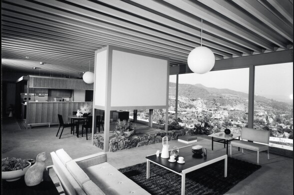 A black and white photo of a living room with mid-century modern furniture. The house overlooks mountains and vistas.