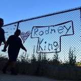 TOPSHOT - People walk past the name Rodney King seen on a chain-link fence surrounding Silver Lake Reservoir in Los Angeles, on June 9, 2020, where a new art installation protesting police brutality spells out, in colourful woven fabric, the names of unarmed African Americans who have been killed by police. - King, who was violently beaten by LAPD officers during his arrest for high speed drunk driving, became a writer after surving police brutality and died in June, 2012 from alcohol poisoning. (Photo by Frederic J. BROWN / AFP) (Photo by FREDERIC J. BROWN/AFP via Getty Images)