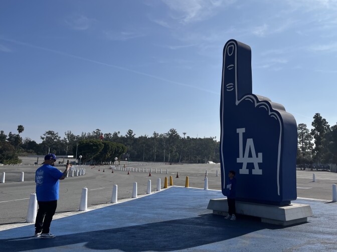 A man takes a photo of a giant replica of a Dodgers foam finger. 
