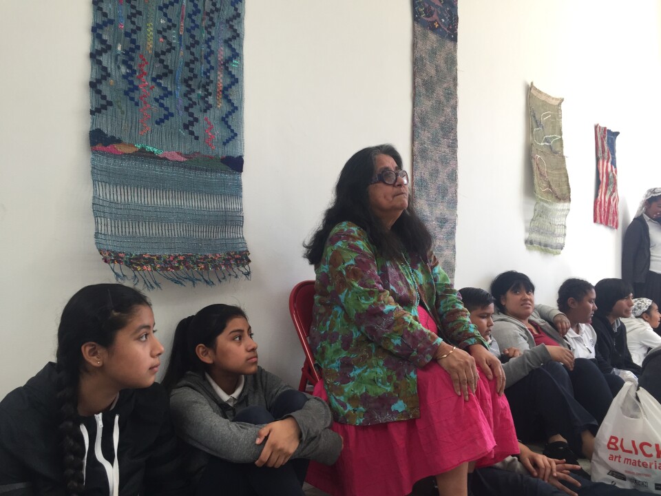 Fiber artist Consuelo Jimenez Underwood listens as students from Clinton Middle present the flowers they made for an exhibition.