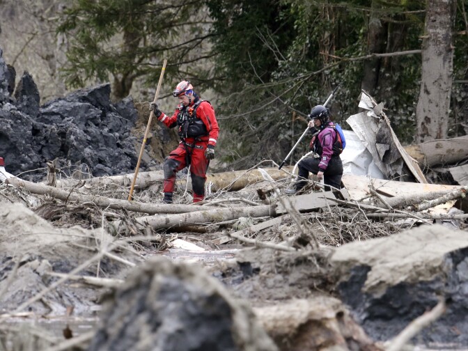 Searchers look through debris from a deadly mudslide Tuesday, March 25, 2014, in Oso, Wash. At least 14 people were killed in the 1-square-mile slide that hit in a rural area about 55 miles northeast of Seattle on Saturday. Several people also were critically injured, and homes were destroyed. (AP Photo/Elaine Thompson)