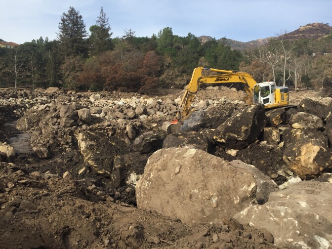 Crews at Cold Springs Basin in Montecito use excavator machines to move giant boulders brought there by the winter's first heavy storm.