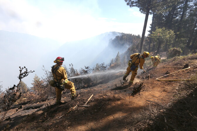 Firefighters hose down hot spots of the King Fire near Pollack Pines, Calif., Monday, Sept. 15, 2014. The fire, which started Sunday has consumed more than 3,000 acres and forced the evacuation of dozens of homes. (AP Photo/Rich Pedroncelli)