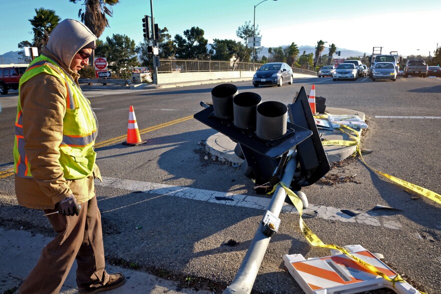 A Los Angeles Department of Transportation worker tends to a fallen traffic light that was blown down by heavy winds in the Van Nuys section of Los Angeles on Saturday, Jan. 24, 2015. A brief but powerful round of Santa Ana winds with gusts topping 60 mph toppled trees and power lines in Los Angeles. About 9,000 customers were without electricity in the San Fernando Valley Saturday morning.