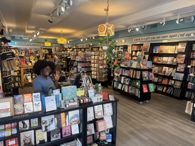 A woman in a blue shirt stands in pages: a bookstore. She is surrounded by books on all sides.