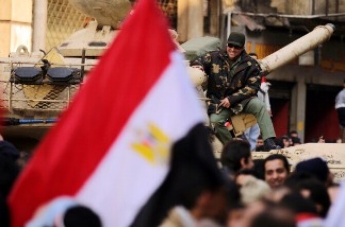 An Egyptian army officer sitting on his tank smiles as he watches anti-government protesters gather in Cairo's landmark Tahrir Square on February 11, 2011.