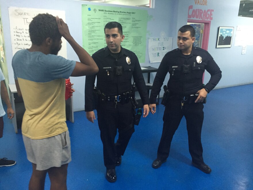 LAPD Officer Oscar Orozco, center, and his parter talk to a manager at a rehabilitation center in downtown Los Angeles who reported a man was assaulting people inside. Officers must turn on their cameras whenever their initiate contact with someone.