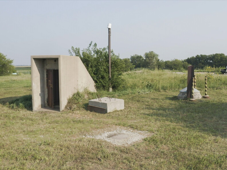 A door rises from a grassy flat area