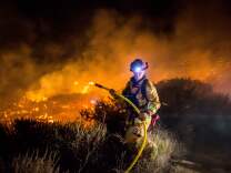 A firefighter works to extinguish the Thomas Fire as it burns past the 101 Highway towards the Pacific Coast Highway in Ventura, California, Dec. 7, 2017. 