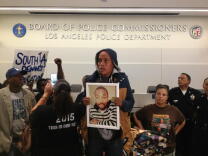 A woman holds a photo of Ezell Ford during a police commissioner meeting on his shooting death on Tuesday, June 5, 2015.
