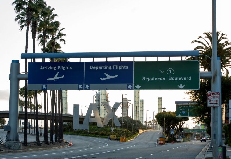 The LAX entrance with a sign that shows three different routes to drive. One goes to the arrivals floor, another to departing, and the last to Sepulveda Boulevard. In the back are the plyons and big LAX sign.
