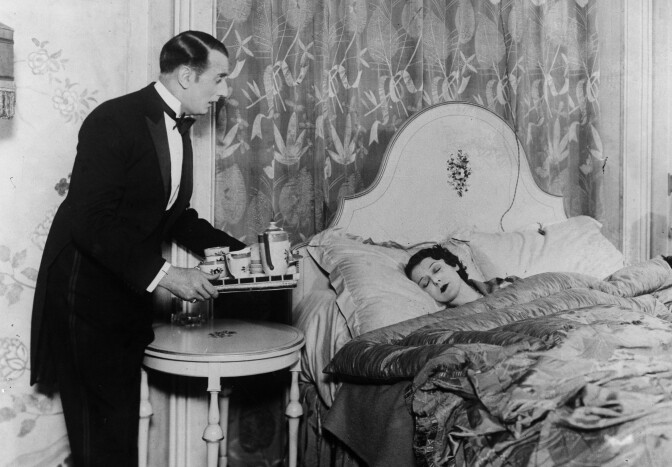 circa 1930:  A butler brings his mistress breakfast in bed. 