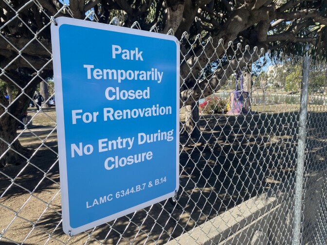 a blue sign with white letters posted to the fence surrounding the park reads: Park temporarily closed for renovation, no entry during closure.