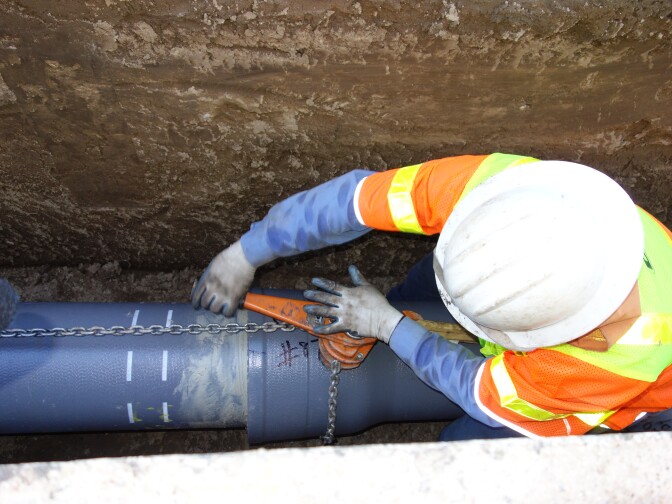 A DWP worker ratchets two sections of earthquake-resistant pipe together. He's listening for the distinctive metallic click that tells him the pipe is locked into place.