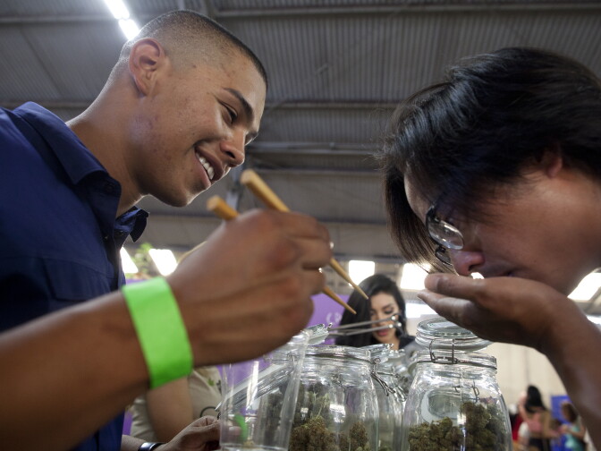 Anthony Guillen, left, shows a sample of a marijuana bud to a patient at the California Heritage Market, the first-ever cannabis farmers market in Los Angeles. The event drew more than a thousand people to an industrial area of Boyle Heights where all types and forms of marijuana were for sale to medical marijuana patients.