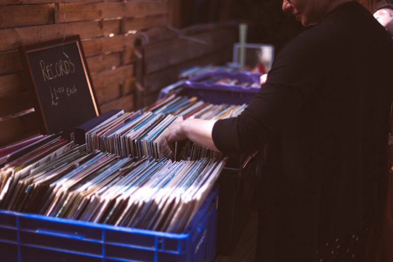 A person rifles through crates of records. There is a sign that says 'Records' at left.