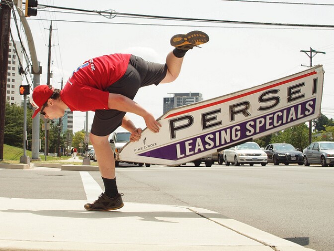 A sign spinner in North Bethesda, Maryland, tosses a sign next to a main road to grab motorists' attention.
