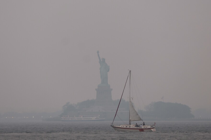 Two people in N-95 masks embrace as smoky air surrounds them.