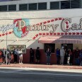 People stand in line under a mural reading: Original Pantry Cafe